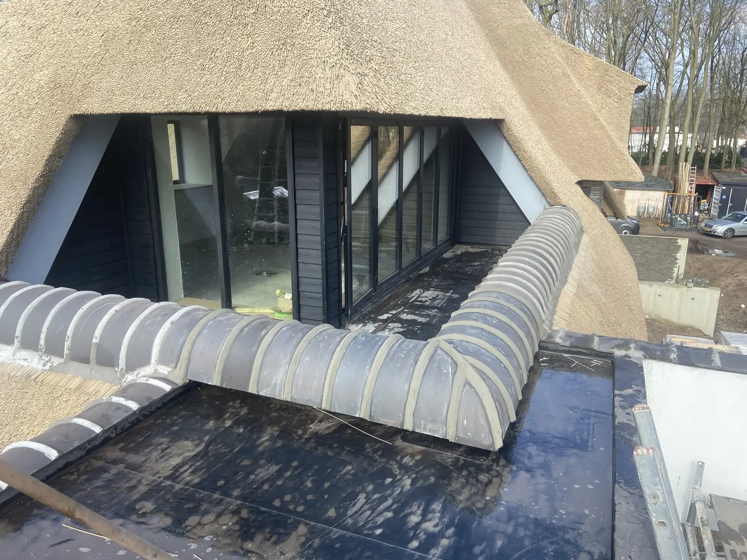 Nokafwerking met vorstpannen en een rieten dakvlak boven een dakterras
