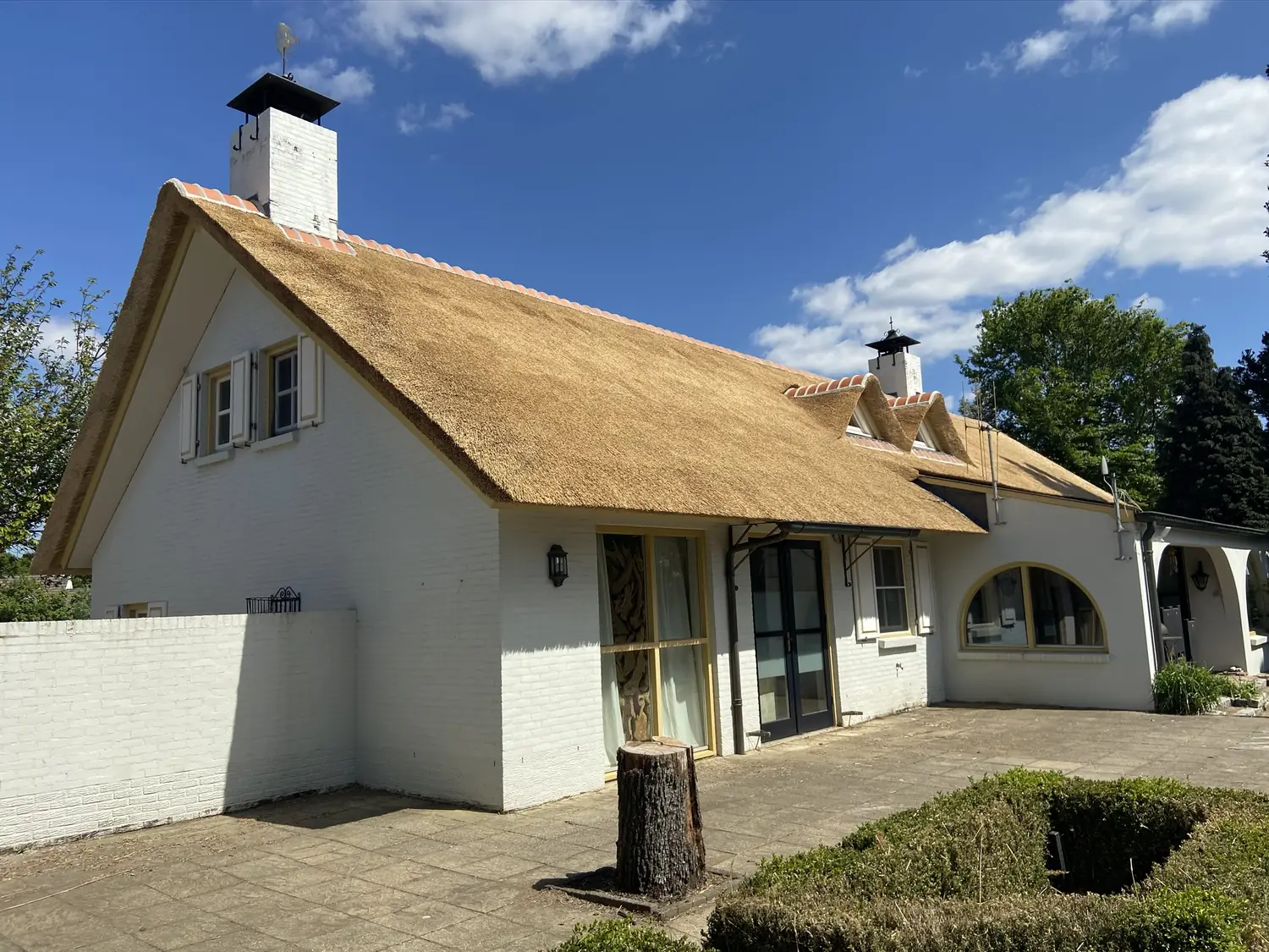 Wit woonhuis met een nieuw rieten dak en twee schoorstenen